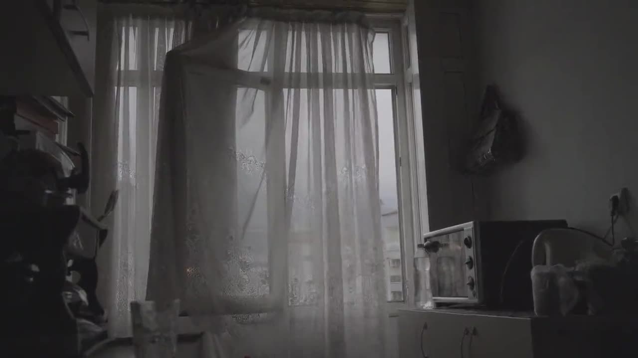 Sheer curtains moving at an open window in a quiet, empty room.